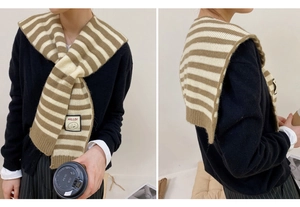 Detail of a brown and beige striped knit shawl with a smiley face logo patch detail