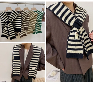Close-up of knitted striped shawl scarf with checkerboard pattern and smiley face patch