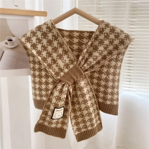 Detail of knitted houndstooth pattern shawl with a minimalist logo tag on ribbed edge