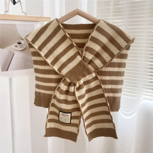 Detail of striped knitted shawl featuring a logo patch and soft thick wool texture