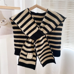 Detail of black and white striped knit shawl with a smile patch on a wooden hanger