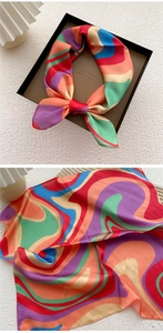 Close-up of vibrant colorful wavy pattern silk scarf inside an elegant black gift box
