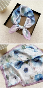 Detail of floral silk scarf showing light blue watercolor flowers and smooth satin texture