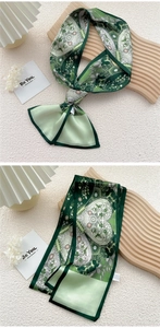 Macro view of green paisley print silk scarf with floral details on a wooden tray