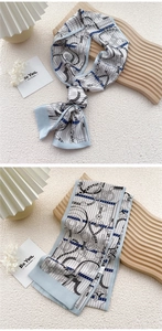 Detail of light blue silk scarf featuring geometric chain patterns and elegant textures