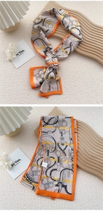 Detail of silk scarf with orange borders and horse harness print on beige background