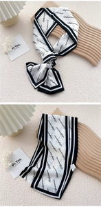 Close-up of black and white striped silk scarf with letter print and smooth texture