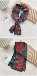 Detail of elegant teal and red abstract floral silk scarf styled on a wooden tray