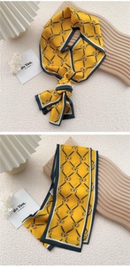 Detail of a yellow silk scarf with horse patterns and navy geometric borders
