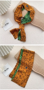 Detail of double-sided twilly silk scarf featuring orange and green floral print patterns
