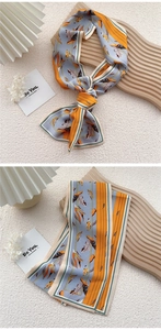 Detail of elegant floral silk ribbon scarf with orange and blue botanical feather print