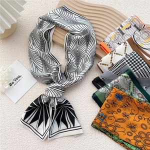 Elegant long skinny silk scarves with various geometric and floral patterns on wood tray