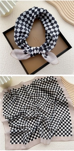 Macro detail of black and white checkerboard silk scarf with pink borders and gift packaging