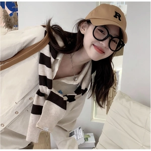 Détail d'un châle en tricot rayé noir et blanc avec une casquette kaki et des lunettes