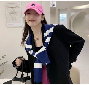 Détail d'un châle en maille à rayures bleues et blanches sur un blazer noir élégant