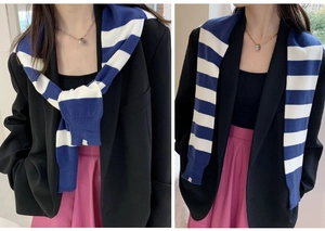 Détail de l'écharpe en maille rayée bleue et blanche drapée sur une veste de costume noire