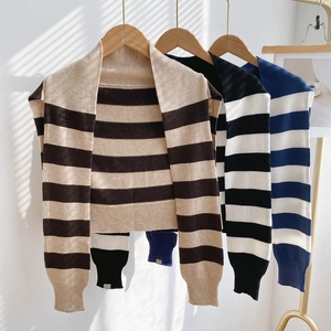 Châle en tricot rayé pour femmes en beige, noir et bleu suspendu sur des cintres