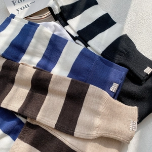 Jambières tricotées à rayures chic en noir, bleu et marron présentées en pile