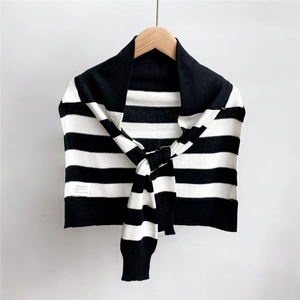 Gros plan d'un châle en tricot rayé noir et blanc avec étiquette d'entretien sur cintre en bois