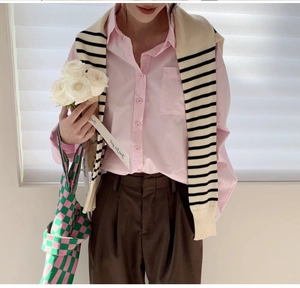 Detail of pink cotton shirt styled with a black and white striped knitted shawl wrap