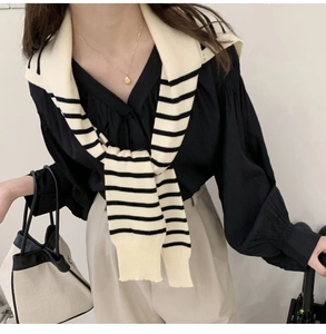 Detail of striped knitted shawl draped over a black shirt for a layered casual look