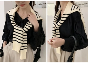 Detail of a black shirt with a striped knit shawl draped over shoulders in a chic style