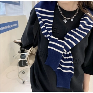 Detail of navy and white striped knitted shawl draped over a casual black sweatshirt