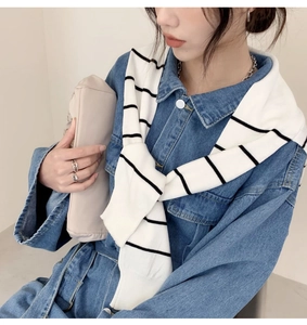 Detail of a black and white striped knit shawl layered over a classic blue denim shirt