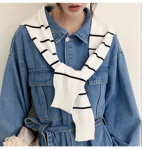 Detail of black and white striped knitted shawl draped over a dark denim shirt