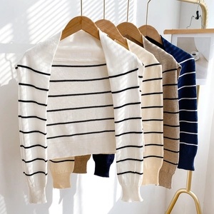 Striped knit shoulder wrap sweaters in four colors hanging on a modern gold garment rack