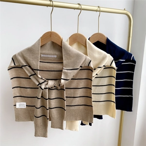 Detailed close-up of striped knit shawls in khaki and navy on wooden hangers