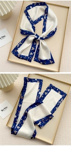 Detail of a blue floral silk scarf tied in a bow against a minimalist textured backdrop