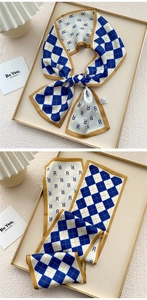 Detail of checkered and letter print silk scarf with golden edge on beige tray