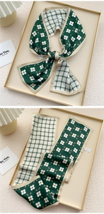 Detail of double-sided silk scarf with green floral and check patterns in a soft macro view
