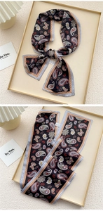 Detail of a black paisley skinny scarf twilly with intricate patterns and silky texture