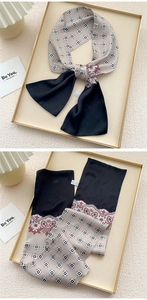 Detail of elegant silk-like long scarf with vintage geometric patterns on a golden tray