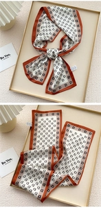Detail of a beige and orange twilly silk scarf with repeated black letter D print pattern