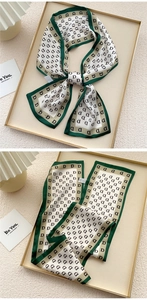 Close-up of silk neck scarf with dark green borders and repeat letter D patterns