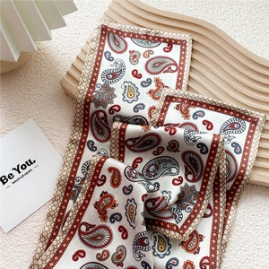 Elegant paisley print silk-like narrow scarf with vintage patterns on a wooden tray