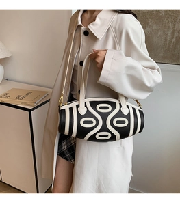 Close-up of black leather bucket bag with white geometric stripes and gold buckles
