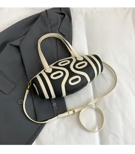 Detail of color-block cylindrical handbag with white geometric patterns and gold hardware