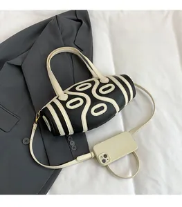 Detail view of oval handbag with contrast patterns compared to a phone size