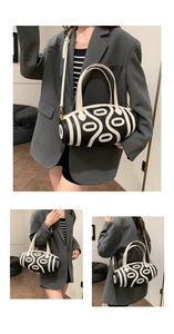 Detail of a black and white striped cylindrical bucket bag with a dZi bead design pattern