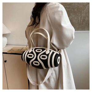 Detail of a black and white cylinder crossbody bag with oval patterns on a leather texture