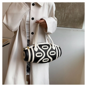 Detail of a cylindrical handbag with black and white geometric patterns and gold zipper