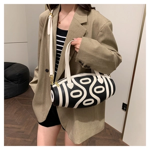 Fashionable black and white cylindrical bag with abstract patterns and gold hardware details