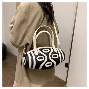 Chic black and white barrel bag with textured oval patterns on a camel blazer