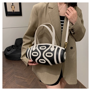 Detail view of a black and white cylinder bag with cut-out pattern on textured leather