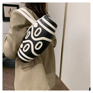 Close-up of cylindrical black and white crossbody bag with unique 3D spiral leather details