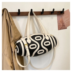 Detailed macro view of black and white barrel bag with geometric swirl pattern on wood
